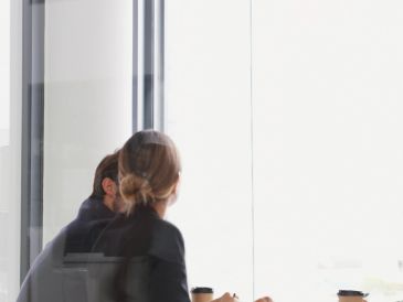 People in a business meeting, seen through glass window.