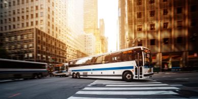 City street with buses and tall buildings at sunset.