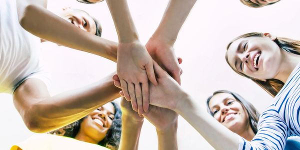 Group of diverse people stacking hands in unity and teamwork.