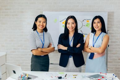 Three confident businesswomen posing with arms crossed in office.