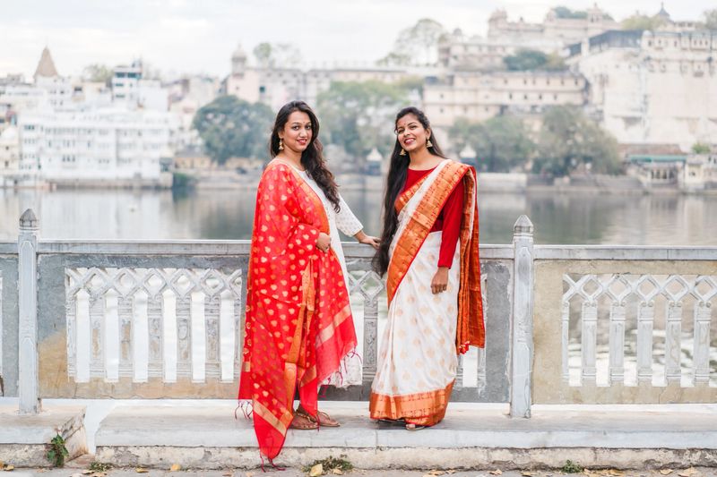 Indian female models at Ambrai Ghat in front of Old City Palace in Udaipur, Rajasthan, India. Hindu girls with traditional Indian dress and sari with red and gold ornaments.