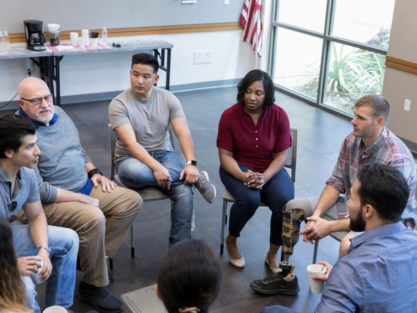 A diverse group having a serious discussion in a support group setting.