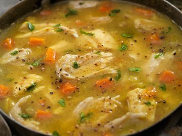 Hearty chicken stew with vegetables in a rustic pan.