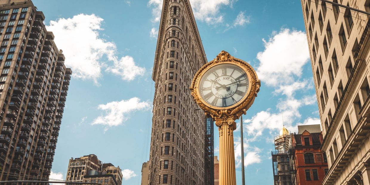 Reloj dorado frente al edificio Flatiron en Nueva York.