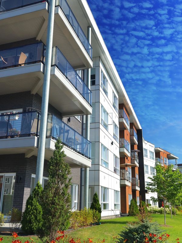 Modern apartment building with balconies under a vibrant blue sky.