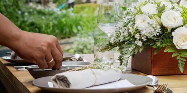 Elegant outdoor table setting with white floral centerpiece and rolled napkin.