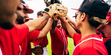 Baseball team joining hands in a huddle.