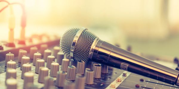 A microphone placed on an audio mixing console with warm lighting.