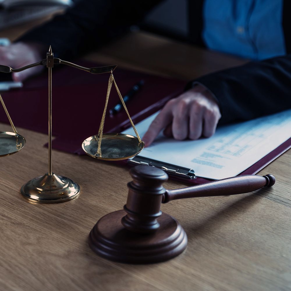 Lawyer reviewing documents with scales of justice and gavel on desk.