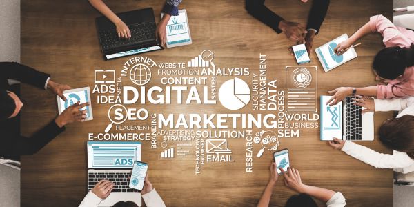 People working on digital marketing with gadgets on a wooden table.