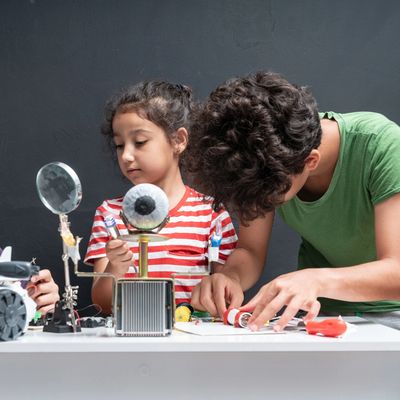 Children engaged in a science project with circuits and models.