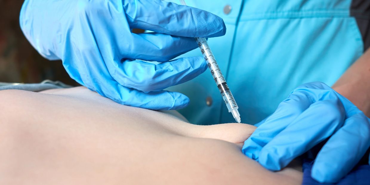 Medical professional administering an injection with a syringe.