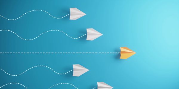 Orange paper plane leading white planes on a blue background.