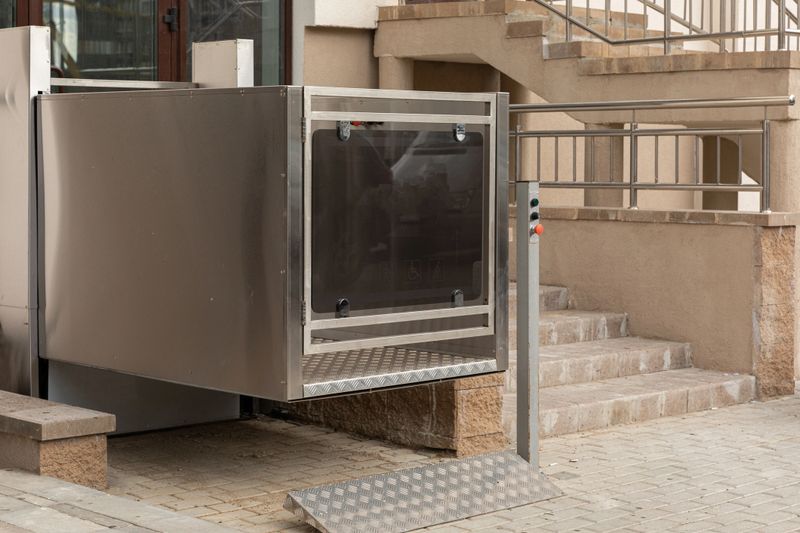 Stair lift, Platform lift, Disabled persons lift near modern apartment facility, diagonal view.
