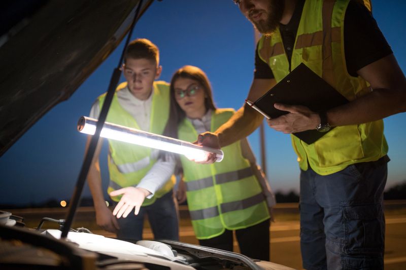 Car mechanic helping young couple in trouble in night