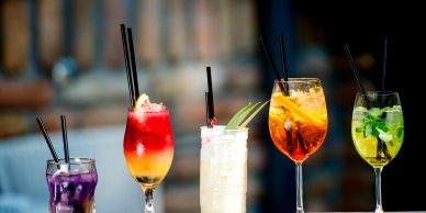 Colorful cocktails lined up with straws.