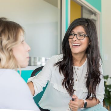 Two women engaged in a positive conversation in an office setting.