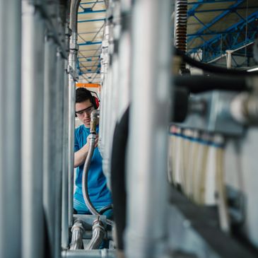 Technician inspecting industrial pipes while wearing safety gear.