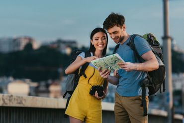 Young couple exploring with a map and backpacks outdoors.