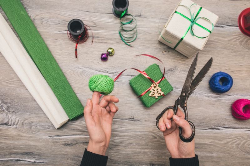 Creative hobby. Gift wrapping. Packaging christmas present boxes. Top view of hands, decoration