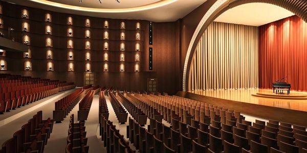 Empty modern auditorium with warm lighting and a grand piano on stage.