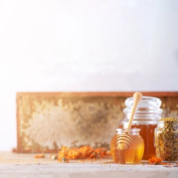 Jar of honey with honey dipper and honeycomb frame.