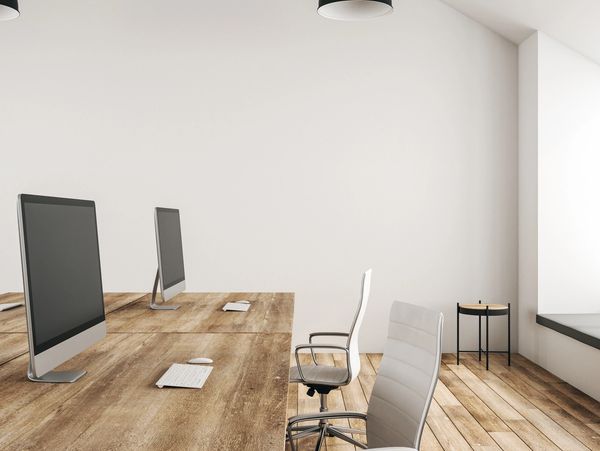 Modern office workspace with wooden desks, computers, and ergonomic chairs.