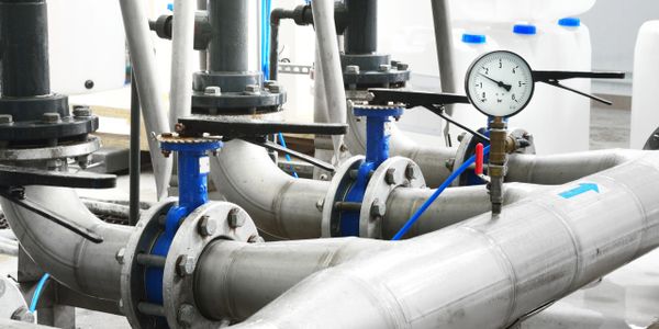 Industrial metal pipes with pressure gauges and valves in a factory setup.