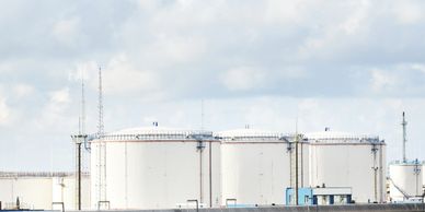 Large white industrial storage tanks under a cloudy sky.