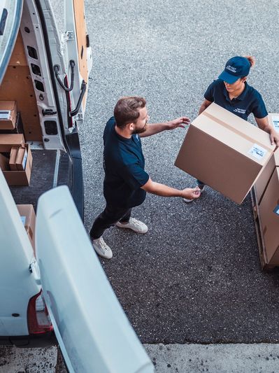 Two men passing a cardboard box during delivery.