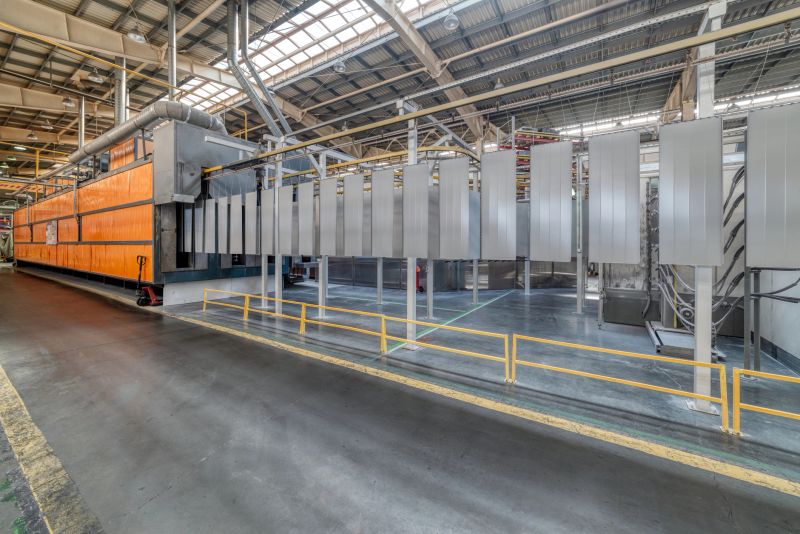 Powder coating line. Metal panels are suspended on an overhead conveyor line. Painting products in an electrostatic field.