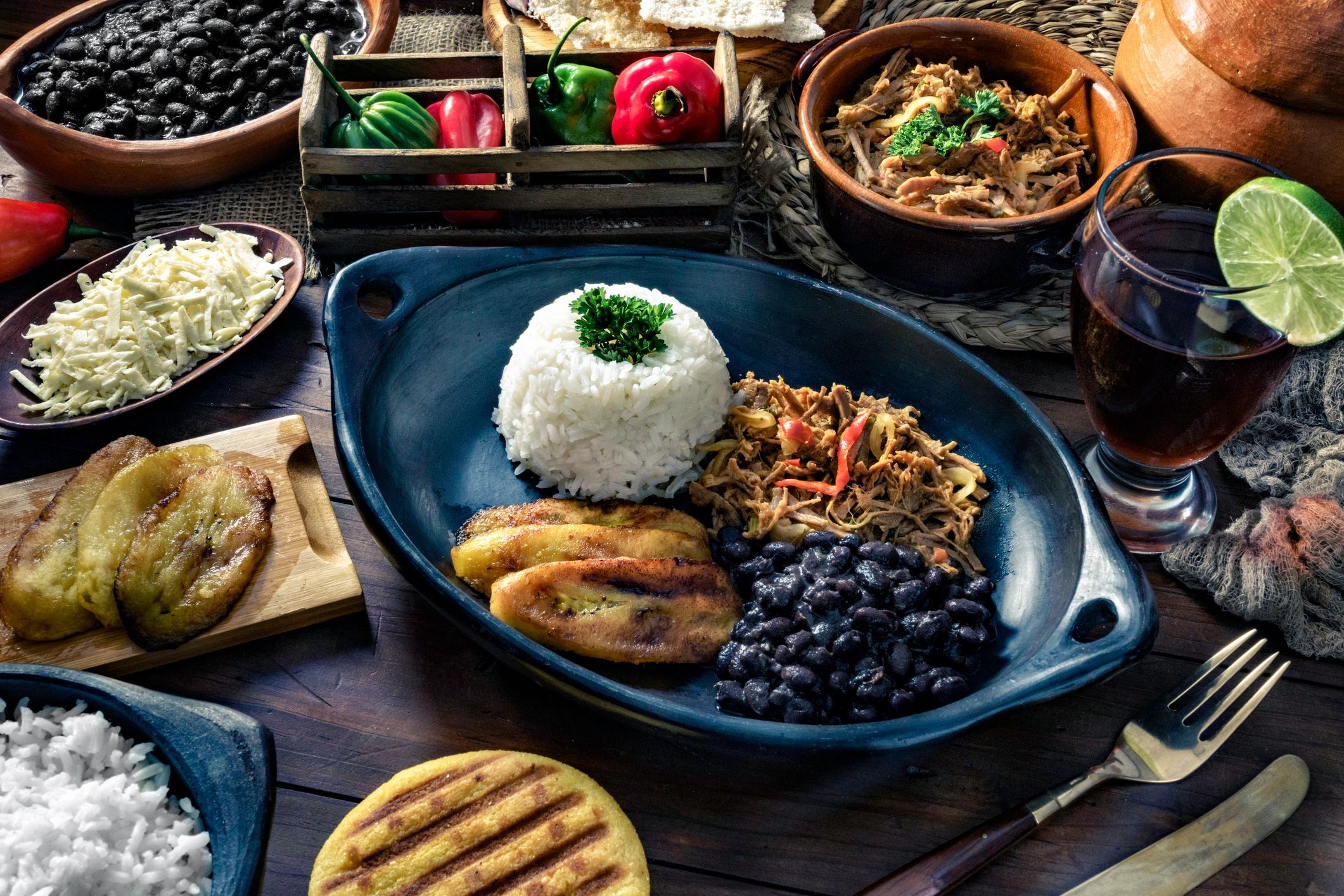 A colorful Latin American meal with rice, beans, plantains, meat, and drinks.