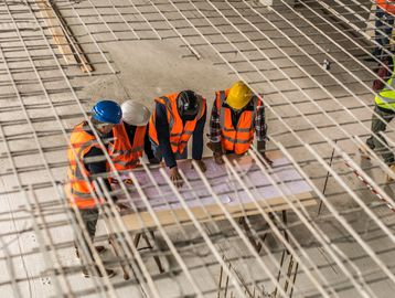 Four construction workers review plans on site.