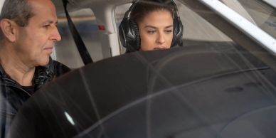 Instructor coaching a female pilot in a cockpit.