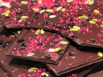 Close-up of chocolate bark with dried fruits and nuts sprinkled on top.