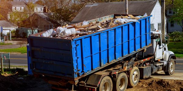 A blue dumpster truck filled with construction debris.
