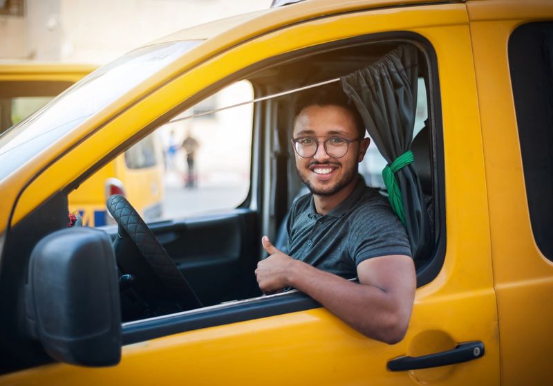 Chauffeur Swiss Taxi Nyon souriant au volant, prêt à prendre en charge ses passagers à Nyon avec ponctualité