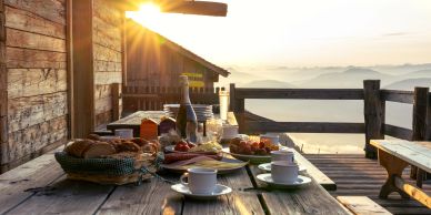 Breakfast set on a rustic table with sunrise in the background.