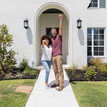 Happy couple celebrating outside new home.
