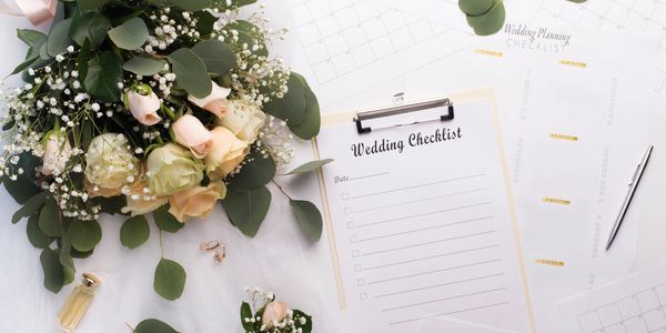 A wedding checklist and planning sheets with flowers and wedding rings.