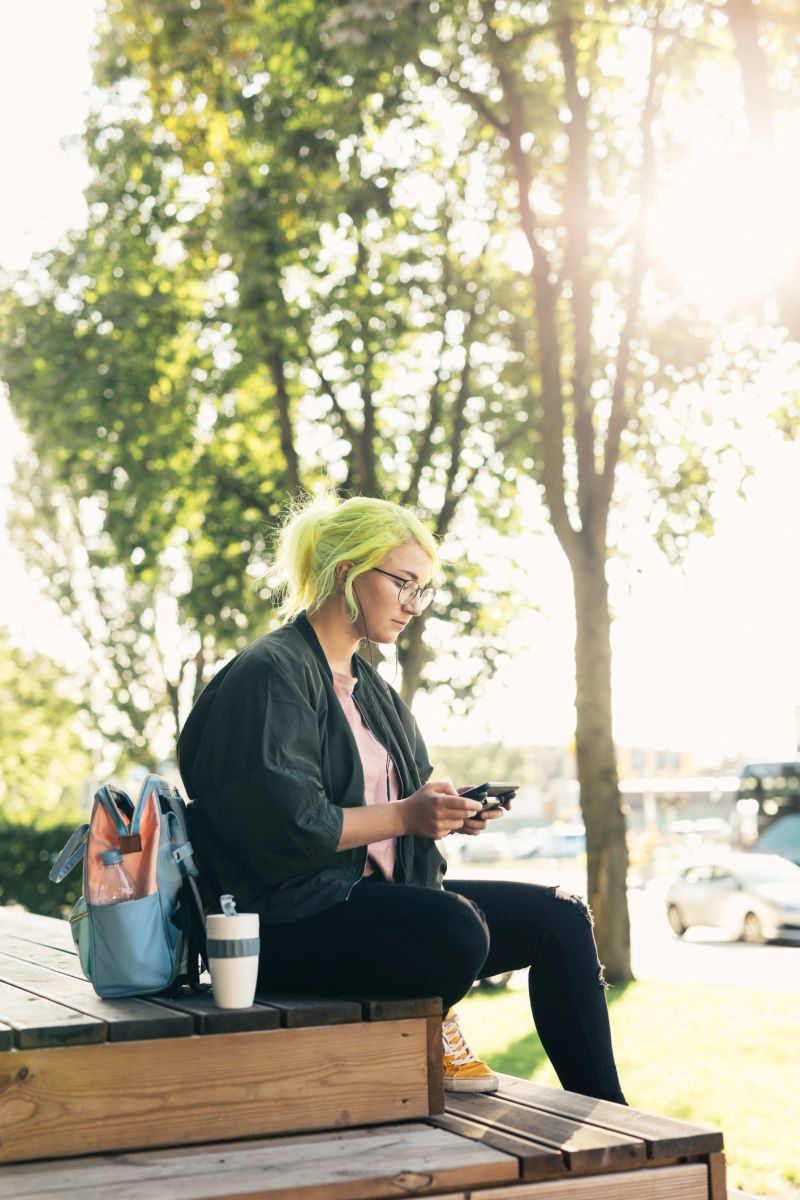 Photo series of authentic dyed hair pokemon go gamer playing mobile games on her smart phone and using reusable coffee cup. Shot at Telliskivi Loomelinnak.