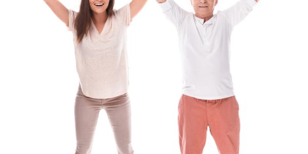 Happy elderly man and young woman celebrating with raised arms and smiling faces.