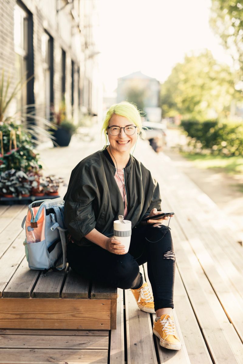 Photo series of authentic dyed hair pokemon go gamer plays mobile games on her smart phone, listens to podcasts and uses reusable coffee cup. Shot at Telliskivi Loomelinnak.