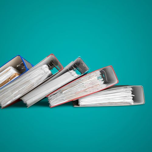 Four colorful binders filled with organized papers on a teal background.