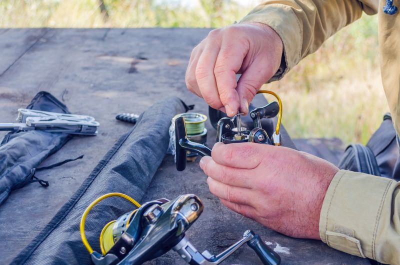 a man repairs a fishing reel with improvised means.