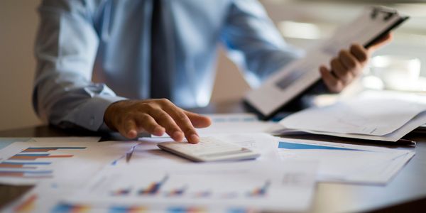 Person in shirt and tie working with documents and calculator.
