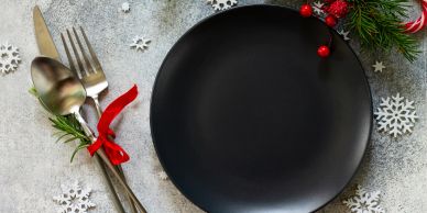 Black plate with festive cutlery and decorations.