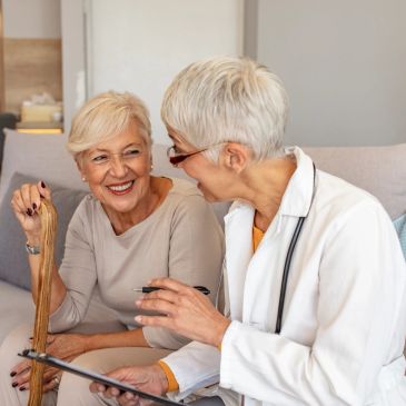 Elderly woman consulting with a female doctor at home.