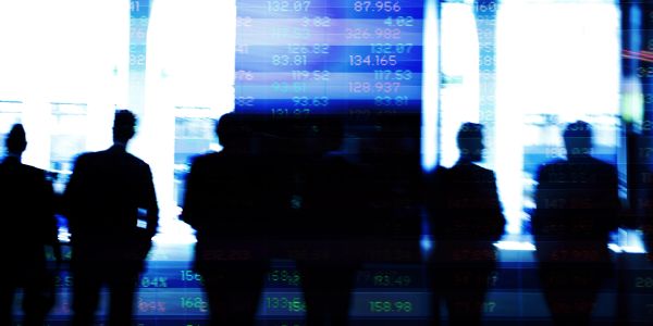 Silhouettes of business people with financial data overlay.