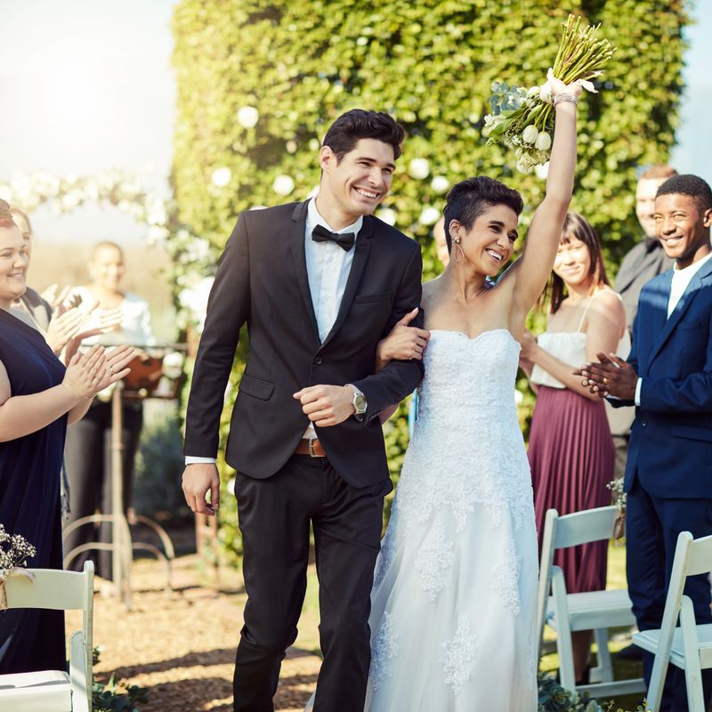 Shot of a happy young couple walking down the aisle together after getting married in a garden